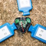 A close-up view of an opened blue, three-panel LED light with visible internal circuitry and wiring, placed on a rough concrete surface.