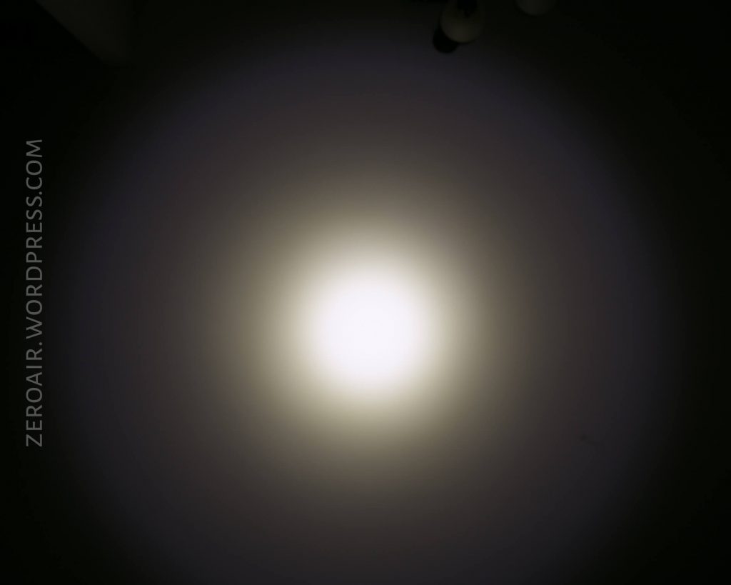 A circular beam of white light is projected onto a dark surface, creating a gradual fade from bright center to shadow. The text ZEROAIR.WORDPRESS.COM appears vertically on the left side.