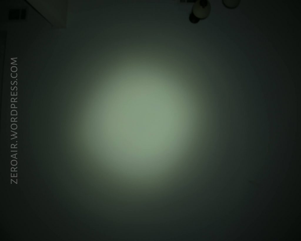A dim circular light beam is projected onto a dark surface. The background is mostly black, with the light fading toward the edges. The text ZEROAIR.WORDPRESS.COM appears vertically on the left side.
