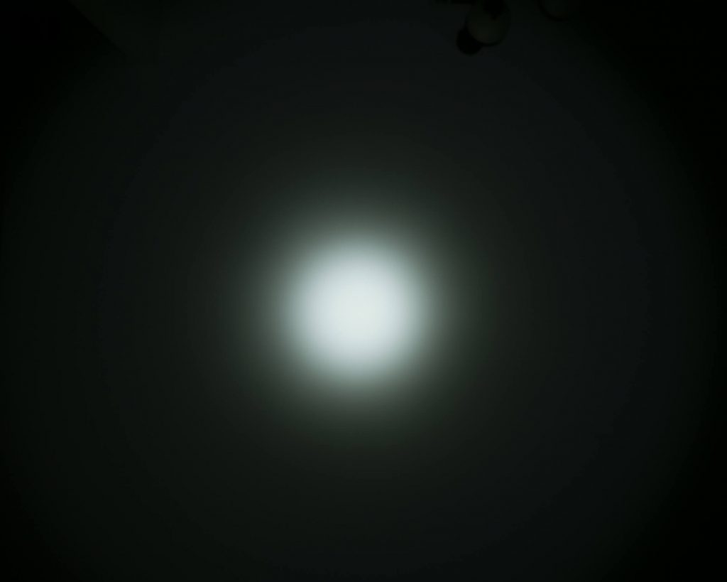 A bright white light is centered in a dark background, gradually fading outward to gray and then to black, creating a circular glow effect.
