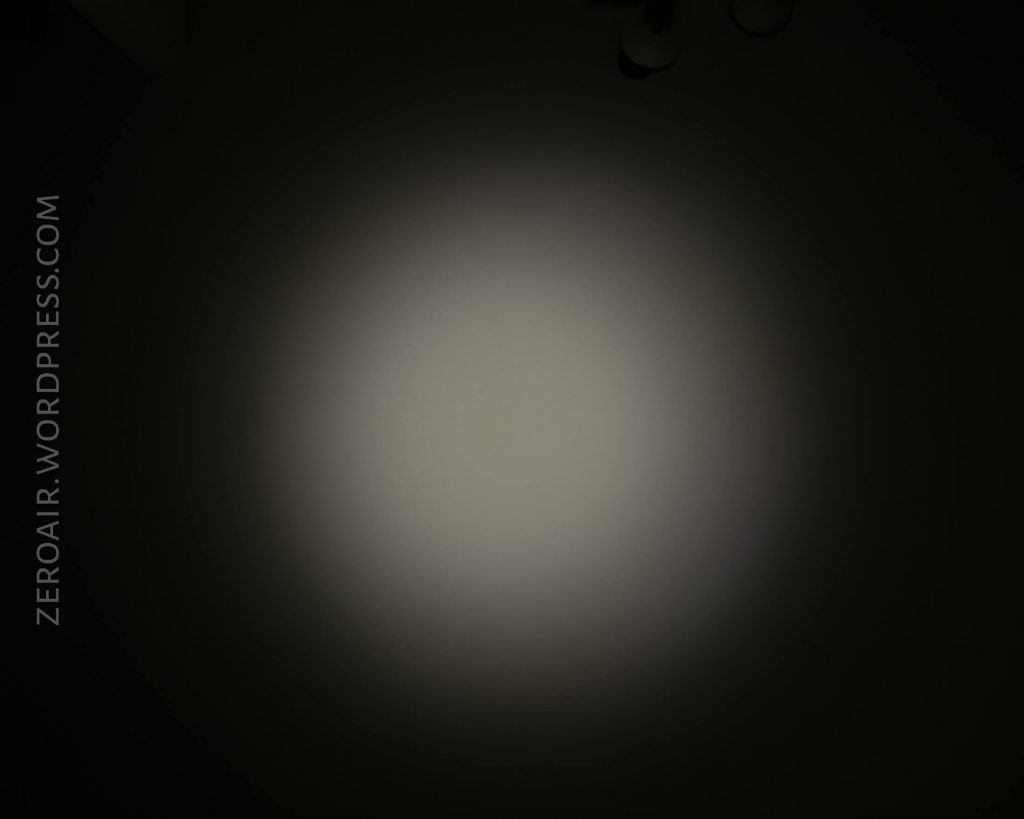 A circular beam of light is projected onto a dark surface, creating a bright center that fades outward. The text ZEROAIR.WORDPRESS.COM runs vertically along the left side.