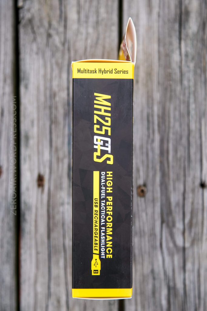 A yellow and black box labeled MH25GTS High Performance Dual Fuel Tactical Flashlight USB Rechargeable from the Multitask Hybrid Series, shown from above on a wooden surface.