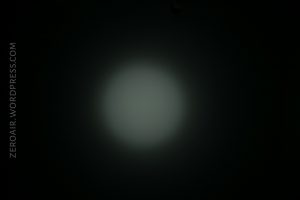A circular white light beam is visible in the center of a dark background. ZEROAIR.WORDPRESS.COM appears vertically along the left side of the image.