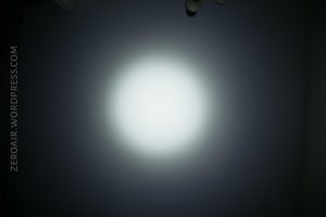 A bright white circular spotlight is projected onto a dark wall. The website text ZEROAIR.WORDPRESS.COM appears vertically along the left side of the image.