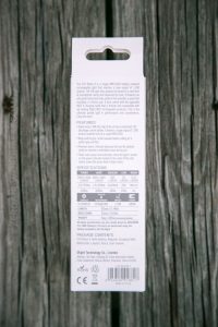 The back of a retail package for the Olight S1R Baton II flashlight, showing product description, features, specifications table, package contents, company information, and certification logos. The package is on a wooden surface.