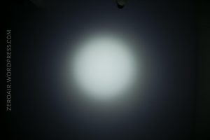A circular white spotlight is centered against a dark background. The words ZEROAIR.WORDPRESS.COM are vertically aligned on the left side.