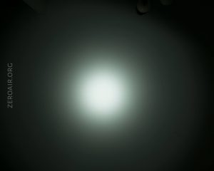 A circular white light beam is centered on a dark background, fading gradually towards the edges. The text ZEROAIR.ORG is vertically aligned on the left side of the image.