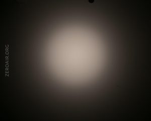 A circular, white beam of light shines on a dark background. The words ZEROAIR.ORG appear vertically along the left side of the image.