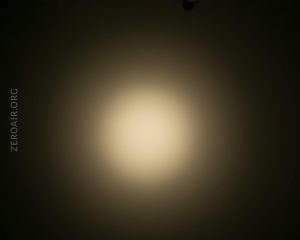A circular beam of soft white light shines against a dark background, creating a gradient effect from bright center to dim edges. The text ZEROAIR.ORG is visible along the left side.