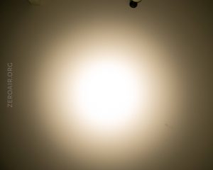 A bright circular light shines on a beige wall, creating a gradient effect from the center outward. The text ZEROAIR.ORG is visible along the left side of the image.