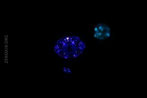 Two circular objects with multiple small lights are illuminated in the darkness, one glowing blue and the other teal. The background is entirely black and the text ZEROAIR.ORG is vertically visible on the left side.