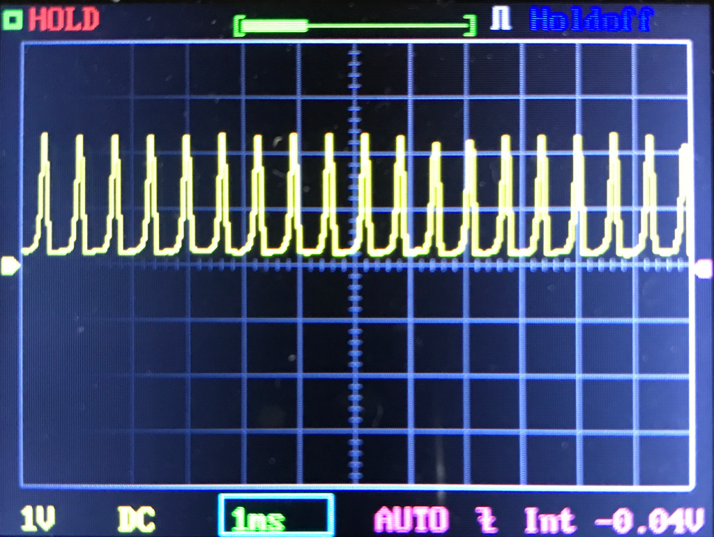 An oscilloscope screen displays a repetitive yellow waveform with sharp peaks and troughs. The horizontal scale is 1 ns per division, and the vertical scale is 1 V per division. HOLD is shown in the top left.