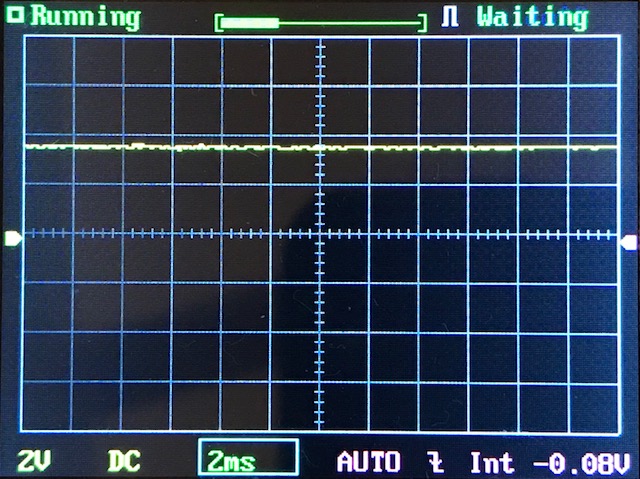 Oscilloscope screen displaying a mostly flat yellow waveform near the center, horizontal and vertical grid lines, and settings at the bottom showing 2V, 2ms, DC, AUTO, and -0.08V offset.