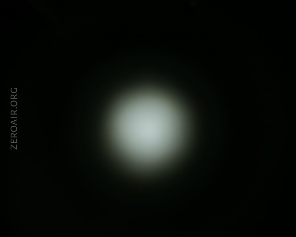 A circular, dim white light is centered against a dark background. The edges of the light gradually fade into darkness. The text ZEROAIR.ORG appears vertically on the left side.