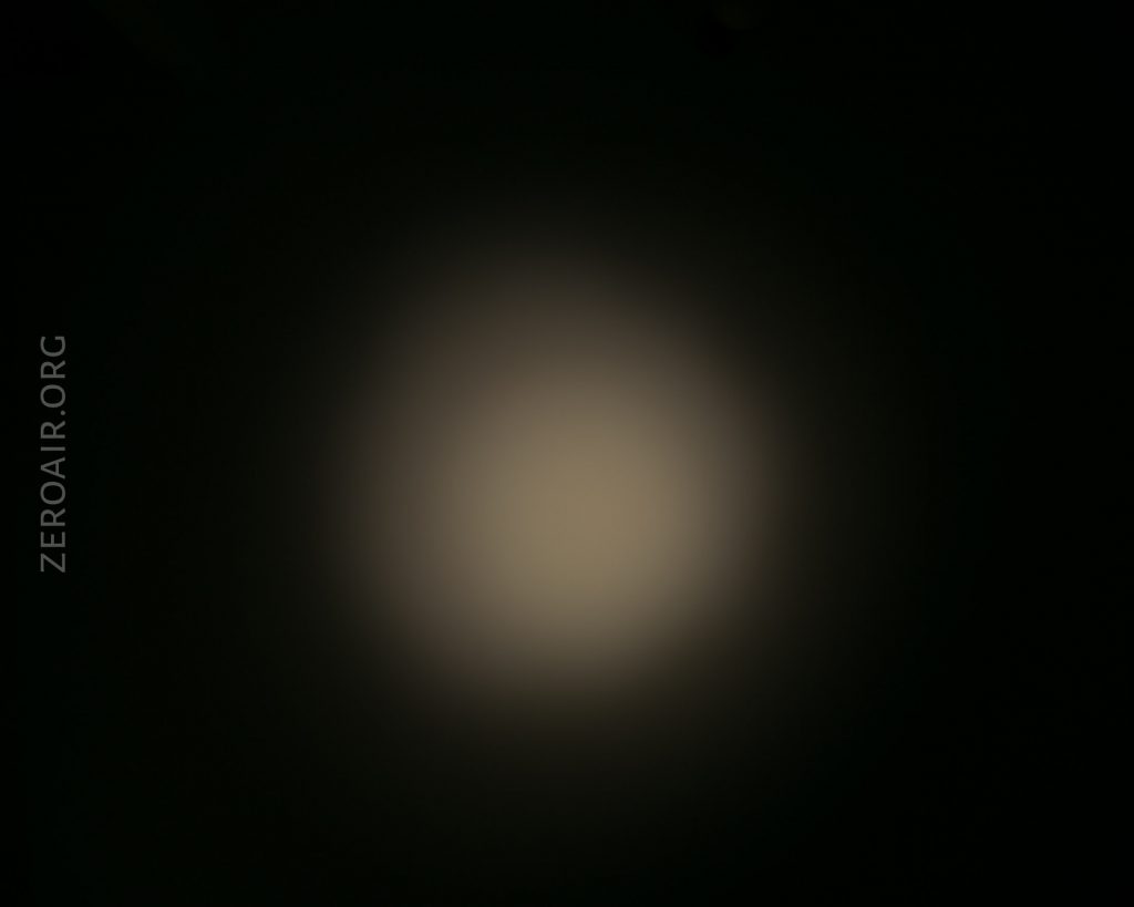 A dim, circular white light is shining on a dark background, creating a soft glow with blurred edges. The text ZEROAIR.ORG appears vertically along the left side of the image.
