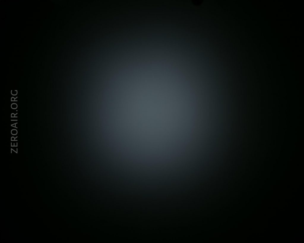 A dim, circular beam of light is centered on a dark background, gradually fading outwards. The text ZEROAIR.ORG appears vertically on the left side of the image.