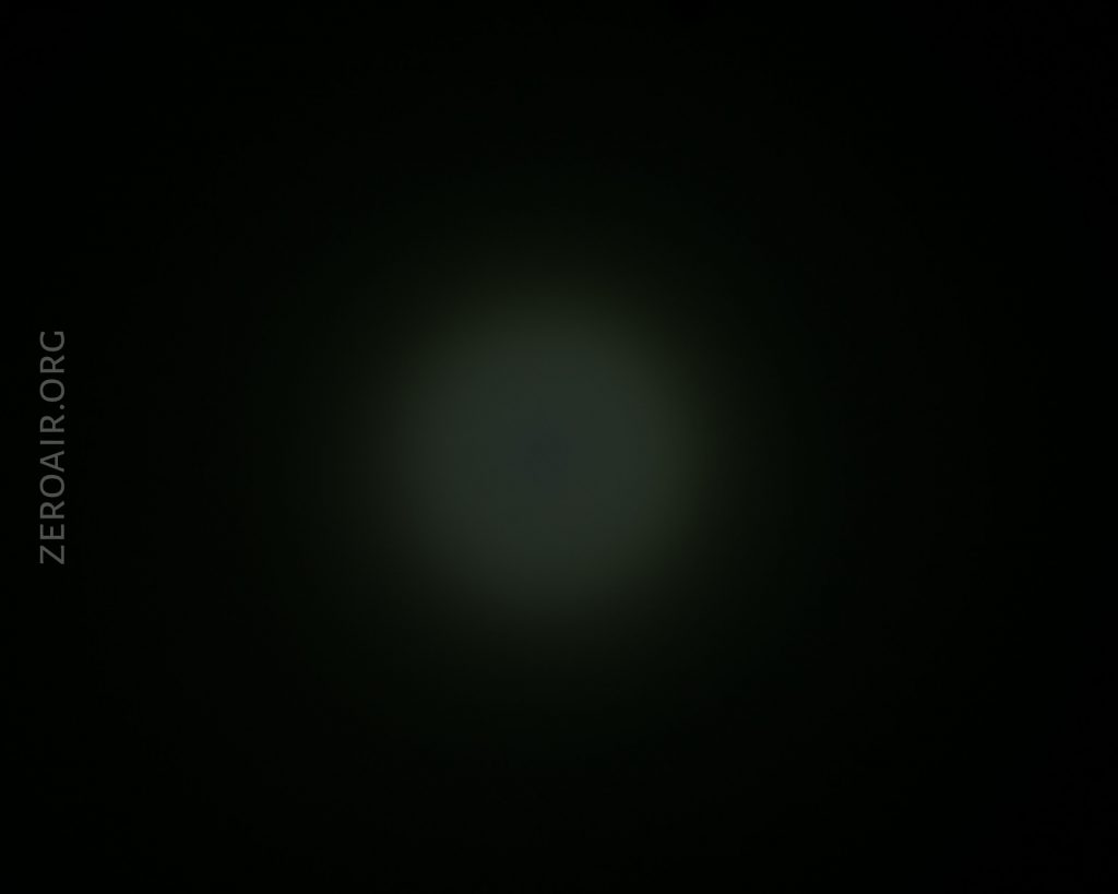 A dim, circular light source is visible in the center of a dark background. The text ZEROAIR.ORG is written vertically along the left side of the image.