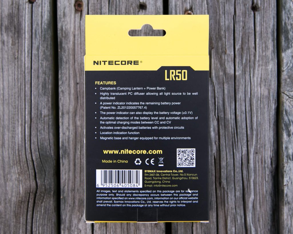 The back of a yellow and black Nitecore LR50 product box is shown on a wooden surface, with features and specifications of the device printed in white text and a barcode at the bottom.
