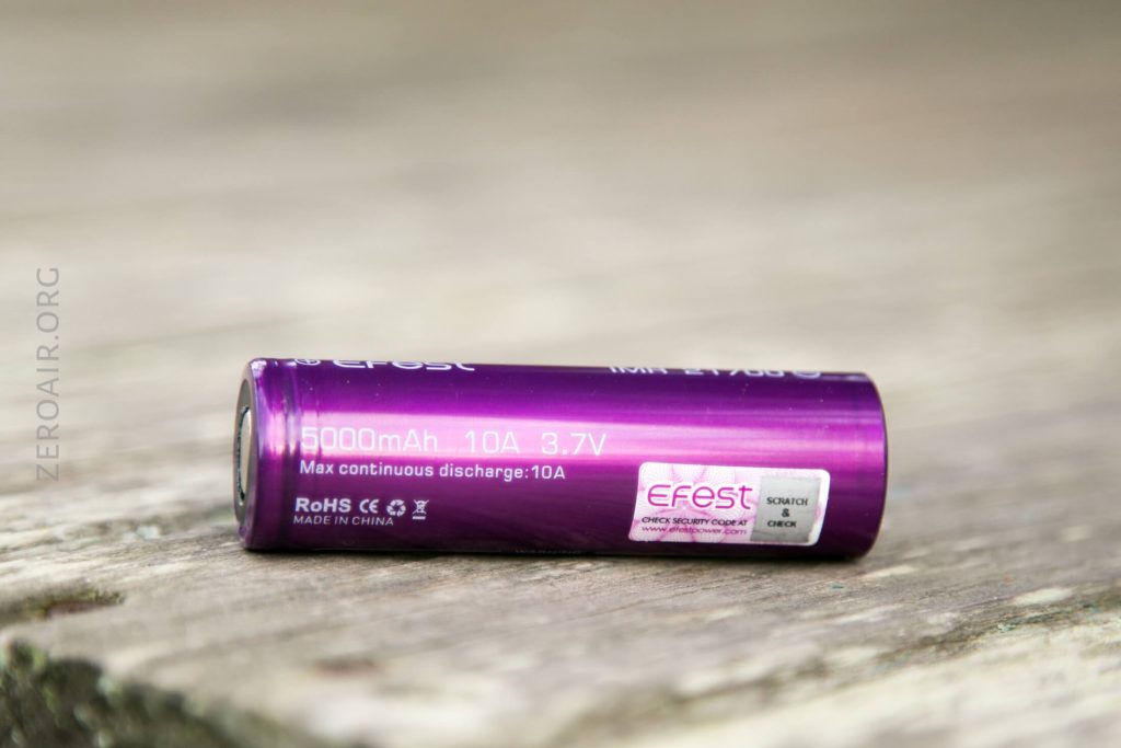 A purple Efest rechargeable battery lies on a wooden surface. The label shows 5000mAh, 10A, 3.7V, and other product details, with a QR code and security check sticker also visible.