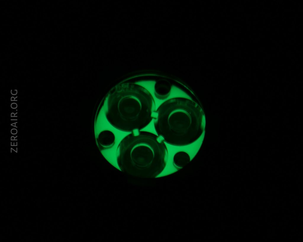 A circular object with three glowing green sections is shown against a black background. The left side displays the text ZEROAIR.ORG in vertical orientation.