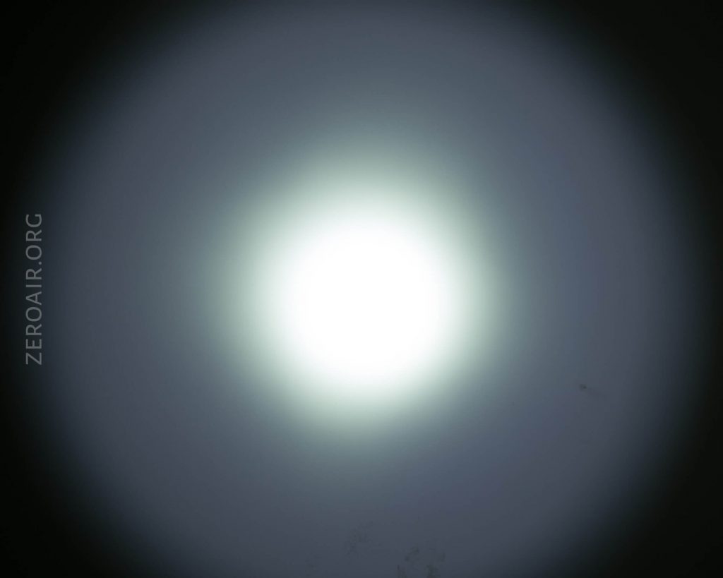 A bright white circular light with a soft blue halo radiating outward on a dark background. The text ZEROAIR.ORG appears vertically along the left side of the image.