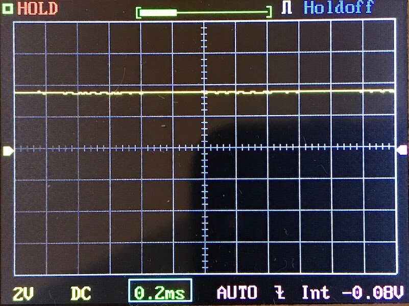 An oscilloscope screen displays a mostly flat yellow waveform near the center. The settings below show 2V per division, DC coupling, a 0.2ms timebase, AUTO mode, and an input voltage of -0.08V.
