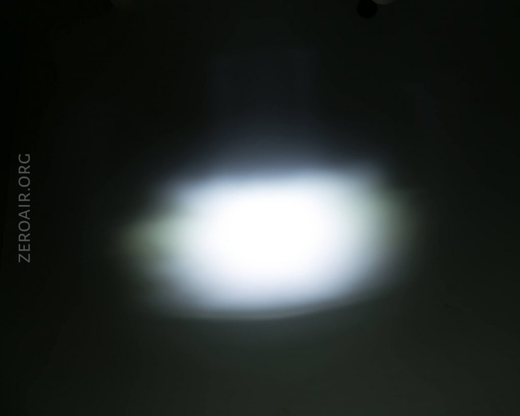 A blurry, bright white light is centered against a dark background with ZEROAIR.ORG faintly visible on the left side.