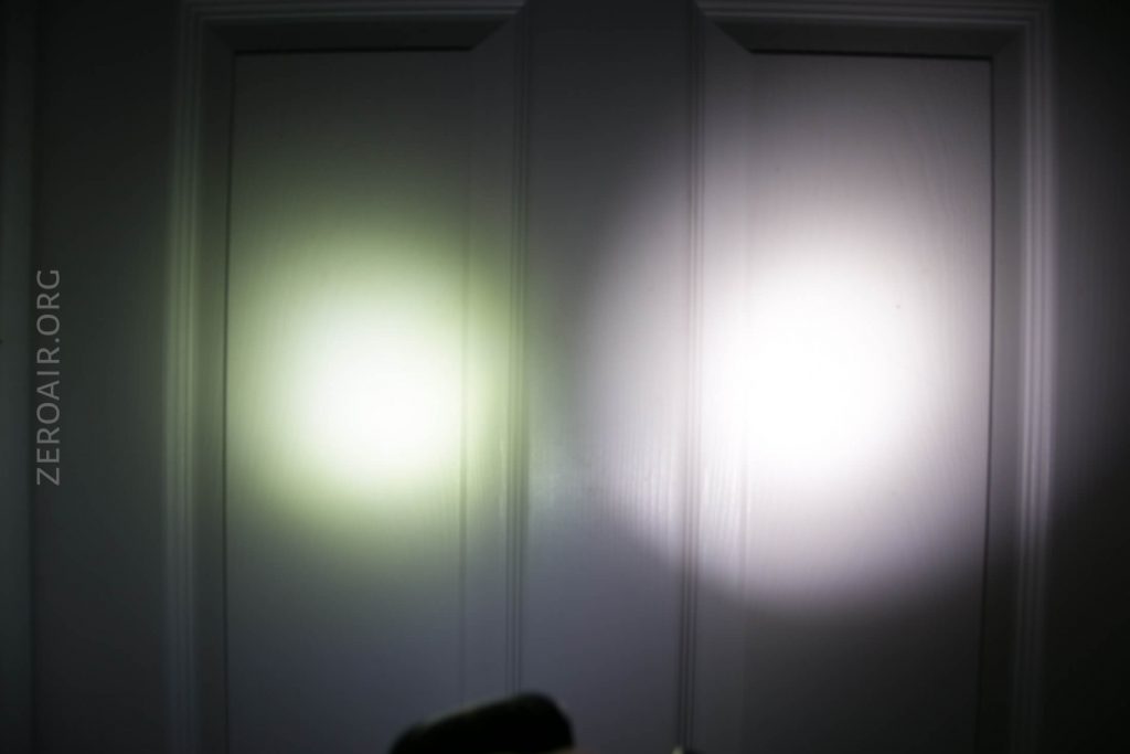 Two bright flashlight beams are shining on a closed white door, side by side, creating circular light spots with soft edges. The text ZEROAIR.ORG is visible vertically on the left side of the image.