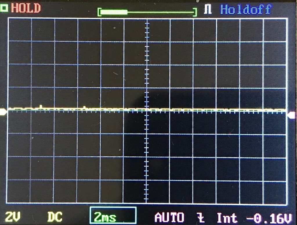 Oscilloscope display shows a flat horizontal yellow line along the center, indicating no significant input signal. Settings: 2V/div, 2ms/div, DC coupling, AUTO mode, holdoff enabled, and voltage at -0.16V.