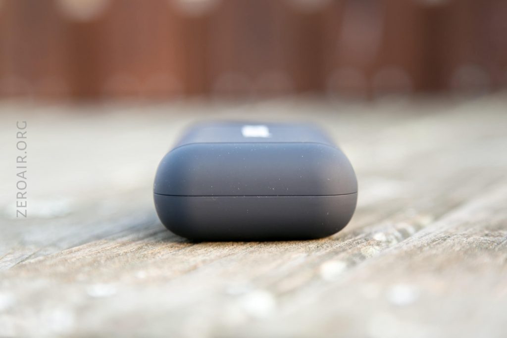 A matte black rectangular case with rounded edges sits closed on a weathered wooden surface, viewed from the front. The background is blurred. The words ZEROAIR.ORG are faintly visible along the left side.