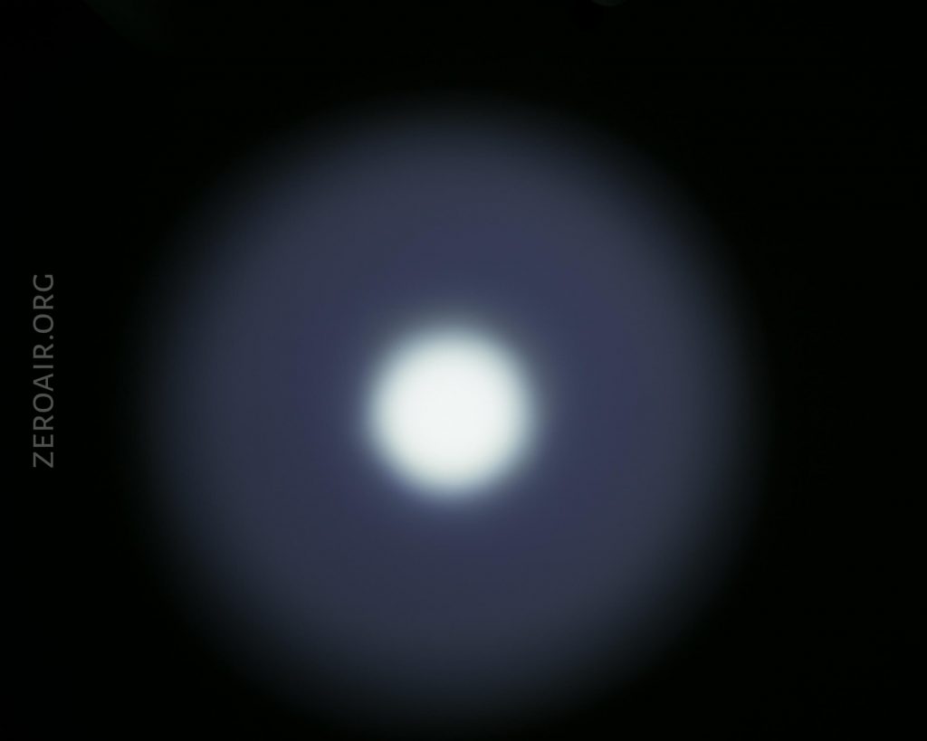 A circular white light is centered against a dark background, surrounded by a blue halo. The website text ZEROAIR.ORG is vertically aligned on the left side of the image.