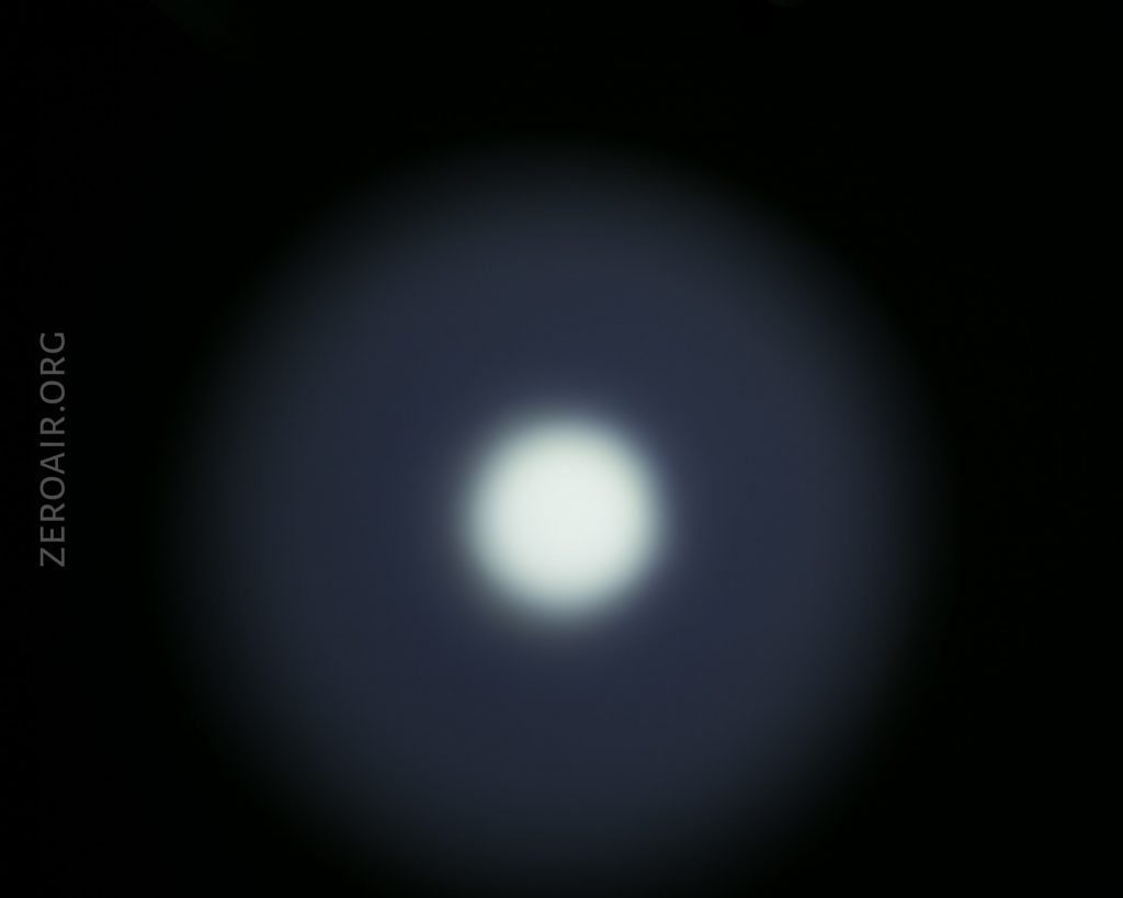A bright white circular light is centered against a dark background, with a soft blue halo surrounding it. The text ZEROAIR.ORG is vertically aligned on the left side of the image.