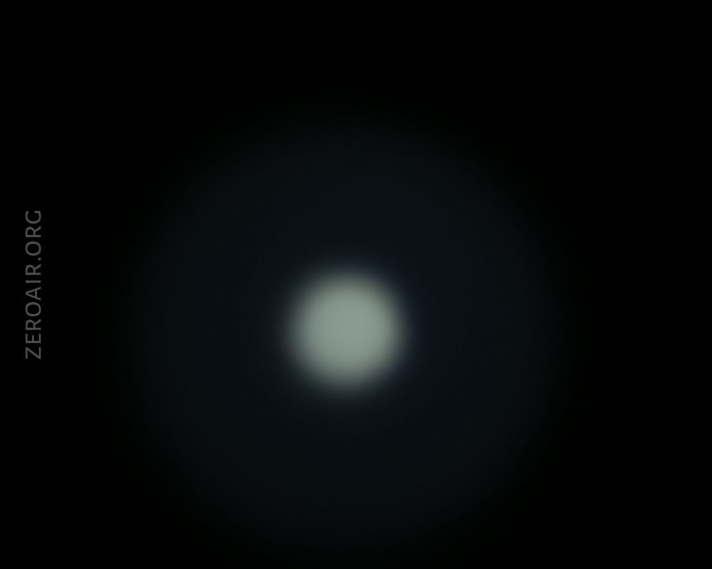 A circular white light is centered against a black background, with a faint halo effect radiating outward. The text ZEROAIR.ORG appears vertically on the left side.