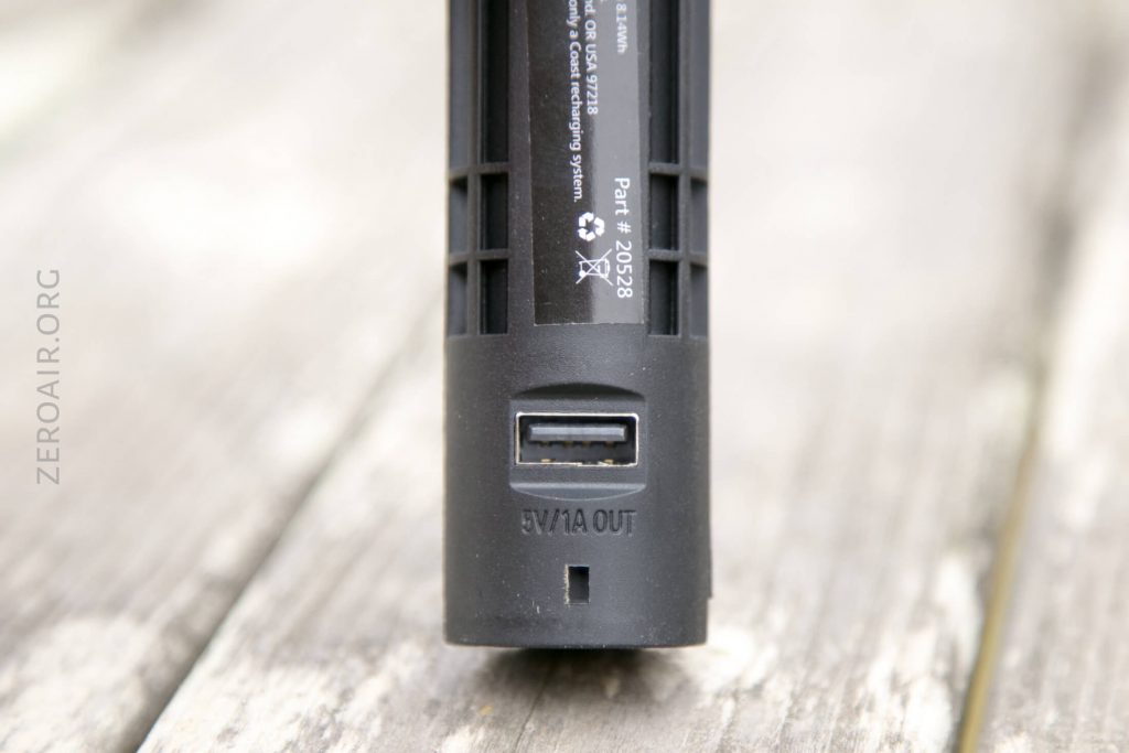 Close-up of the bottom of a black electronic device with a USB port labeled 5V/1A OUT and some text above it, placed on a weathered wooden surface.