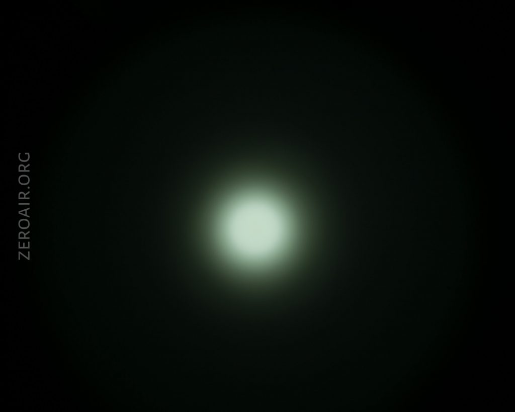 A circular, bright white light is centered against a dark background, with a soft halo effect radiating outward. The text ZEROAIR.ORG appears vertically along the left side.