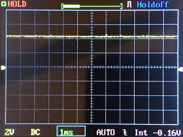 Digital oscilloscope screen displaying a flat yellow waveform near the center, indicating minimal signal variation. Grid, measurement units, and settings such as 2V, 1ms, AUTO, and -0.16V are visible.