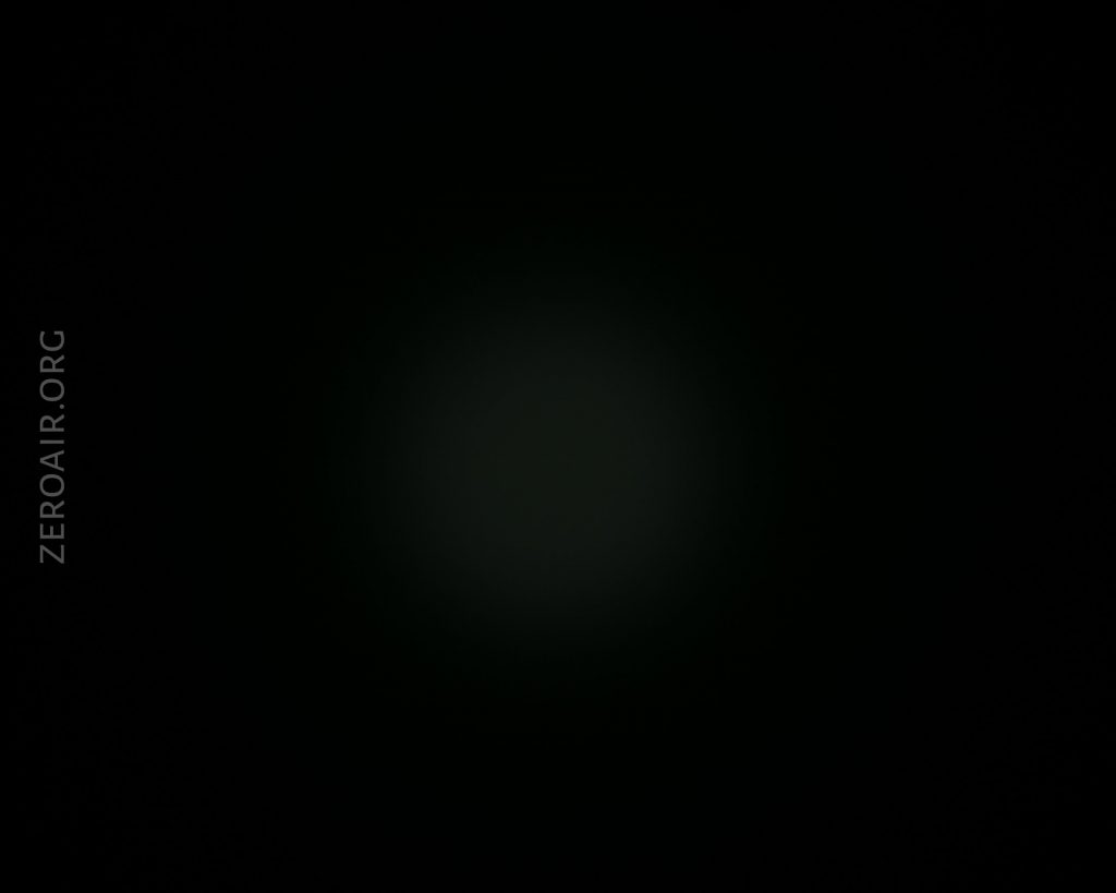 A black image with a faint, circular, diffused gray spot in the center. The text ZEROAIR.ORG appears vertically along the left side.
