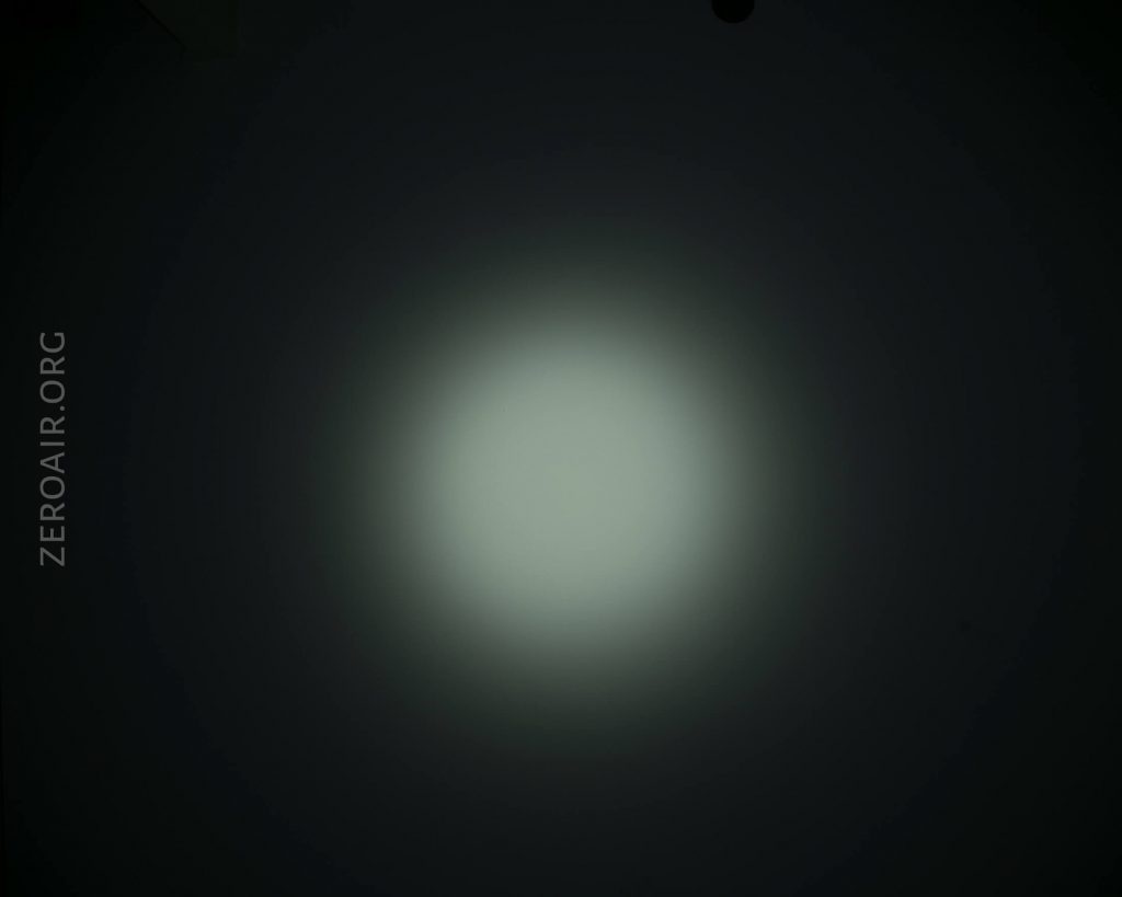 A circular, diffused white light beam is centered against a dark background. The left side of the image features the text ZEROAIR.ORG in a vertical orientation.
