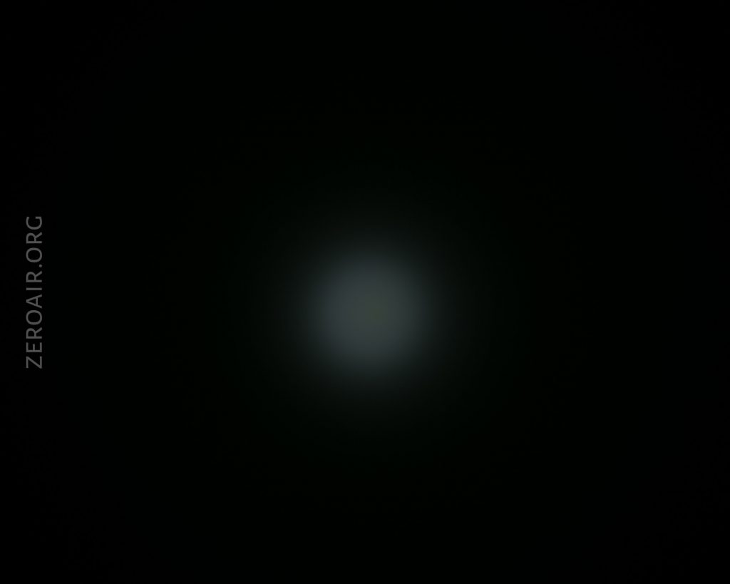 A dim, circular white light spot is visible in the center of a dark background. The words ZEROAIR.ORG appear vertically along the left side of the image.