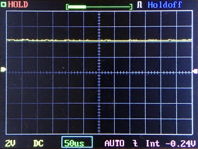 An oscilloscope screen displays a flat yellow signal line near zero, with settings showing 2V per division, 50 microseconds per division, DC coupling, and an average voltage of -0.24V.