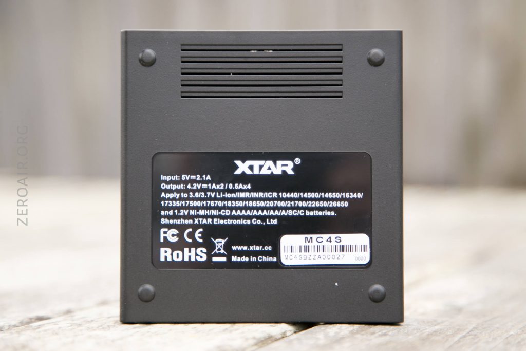 A close-up view of the bottom of an XTAR device showing product specifications, model MC4S, certification logos, and a barcode on a black label; Made in China is also visible.