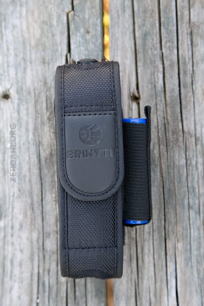 A black Brinyte-branded fabric flashlight holster with a blue flashlight partially visible on the right side, placed vertically on weathered wooden planks.