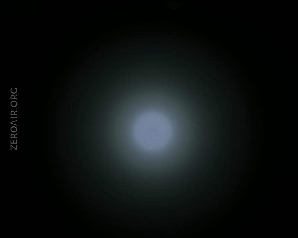 A circular white light is centered against a dark background, creating a bright spot with a gradient halo effect. The text “ZEROAIR.ORG” appears vertically on the left side of the image.