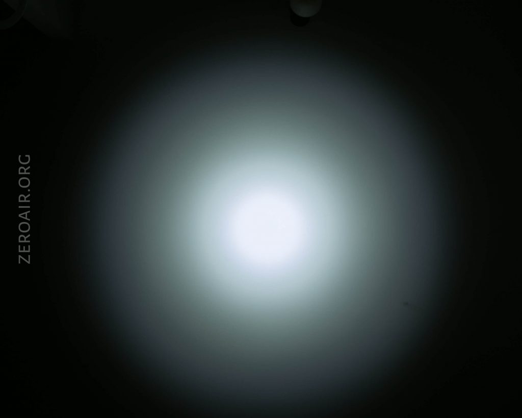 A bright white circular light beam is projected onto a dark background, creating a gradient effect from the center outward. The text ZEROAIR.ORG appears vertically along the left side of the image.