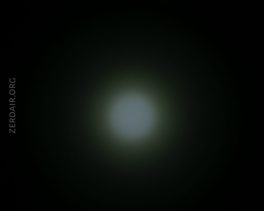 A dim, circular white light is centered against a dark black background, gradually fading outward. The text ZEROAIR.ORG appears vertically on the left side.