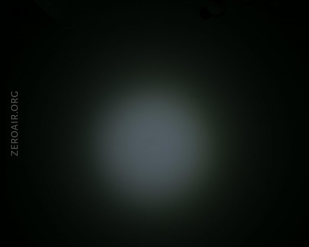 A dim circular spotlight is shining on a dark surface, creating a faded white center with a gradual gradient to black. The text “ZEROAIR.ORG” is vertically aligned on the left side of the image.
