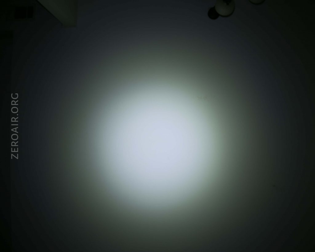 A round, bright white light is projected onto a dark wall, creating a gradient halo effect. The text ZEROAIR.ORG is vertically aligned on the left side of the image.