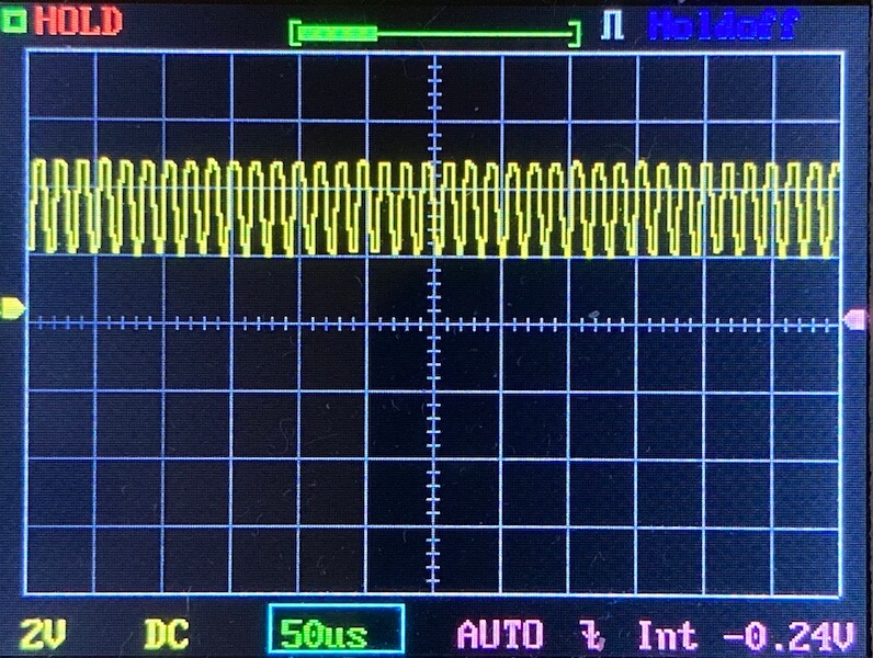 Oscilloscope screen showing a repeating, evenly spaced square wave signal in yellow. The horizontal scale is set to 50 microseconds per division, and the vertical scale to 2 volts per division.