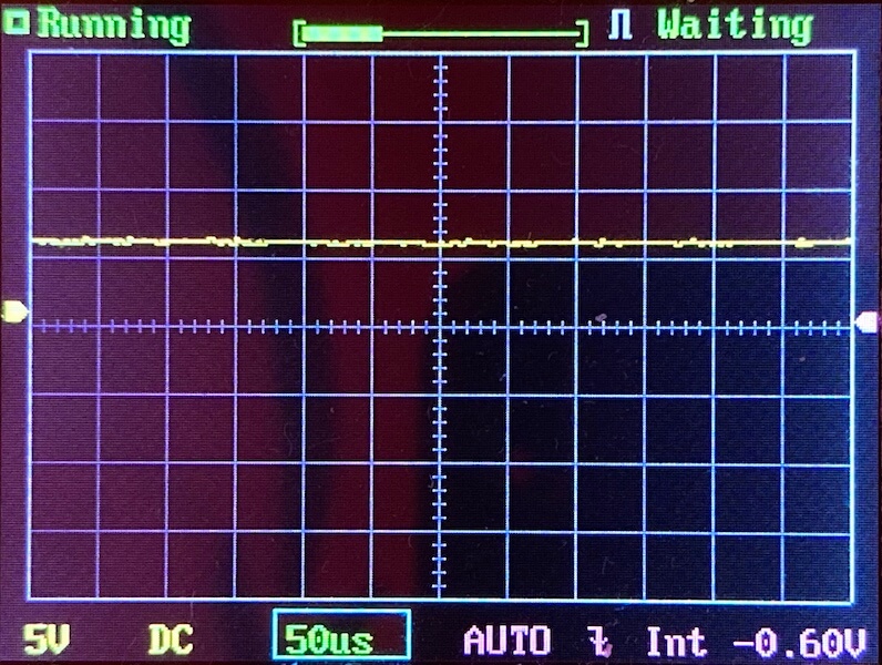 Oscilloscope screen displaying a mostly flat yellow waveform with minor noise, set to 5V per division and 50 microseconds per division. Indicators read Running and Waiting at the top.