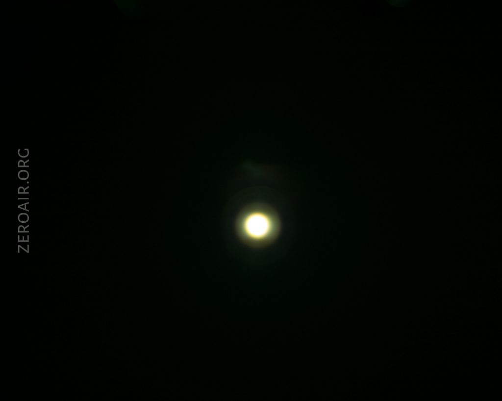 A bright white circular light appears in the center of a dark background. The word ZEROAIR.ORG is faintly visible along the left side of the image.